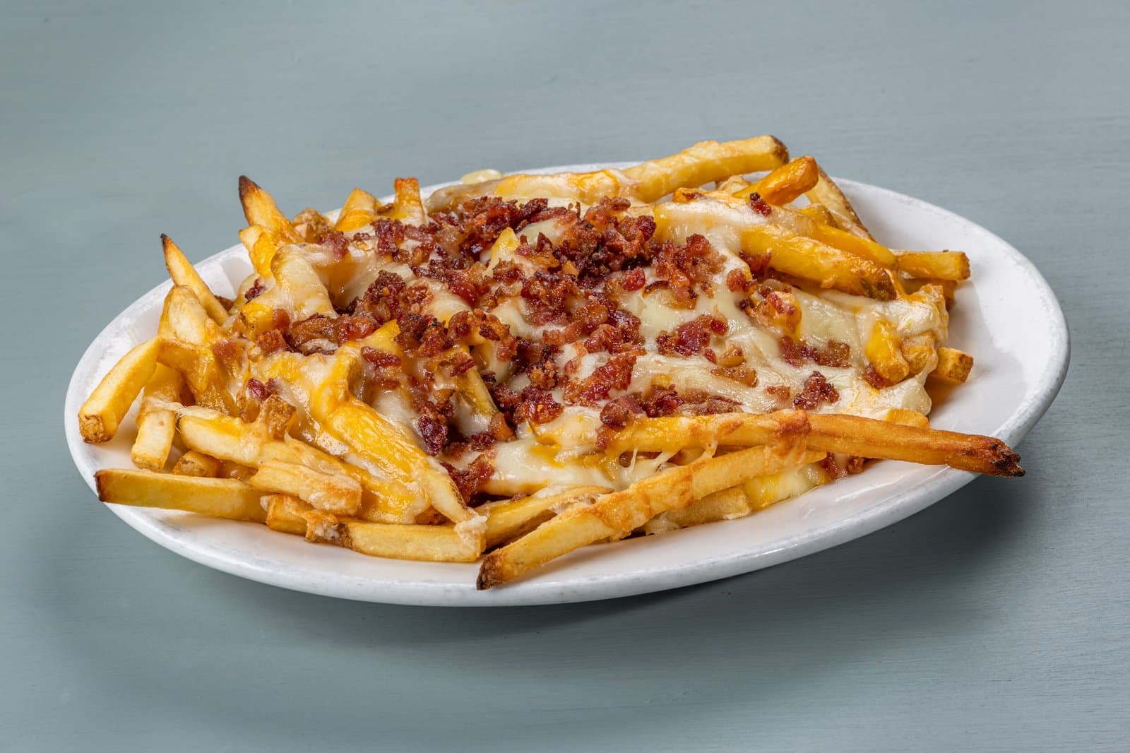 Bacon cheese fries on an oval platter