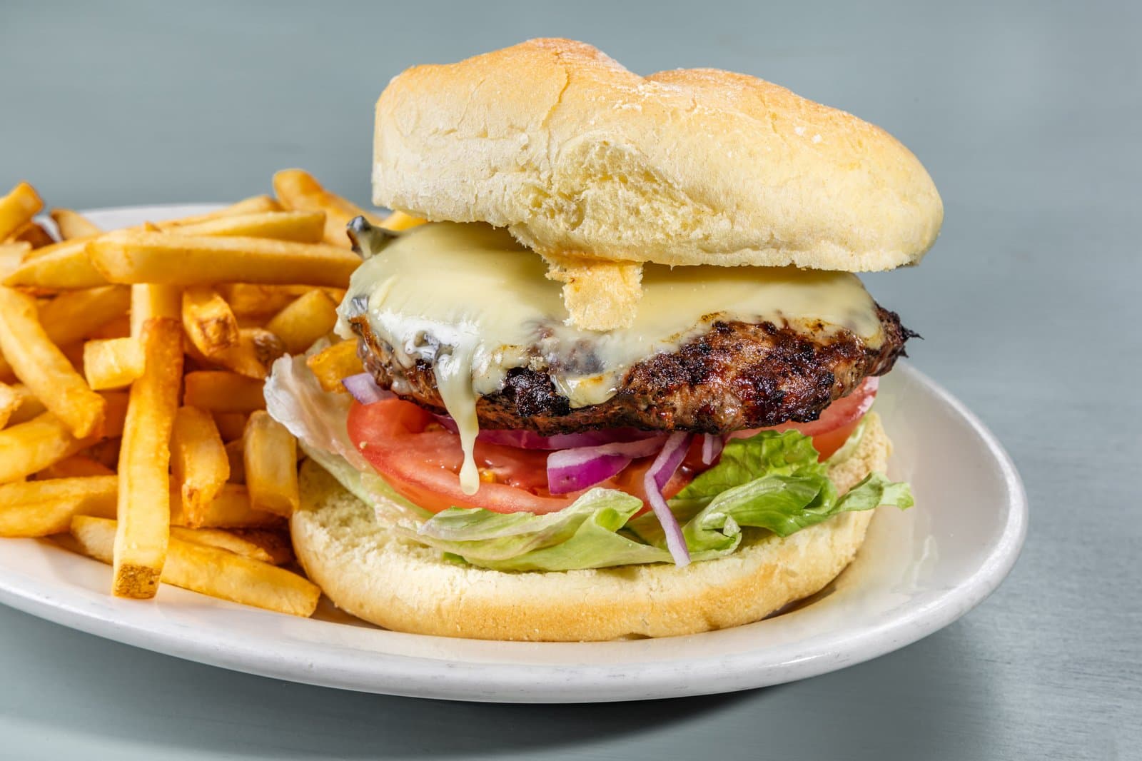 Cheeseburger with lettuce, tomato, and red onion, served with fries