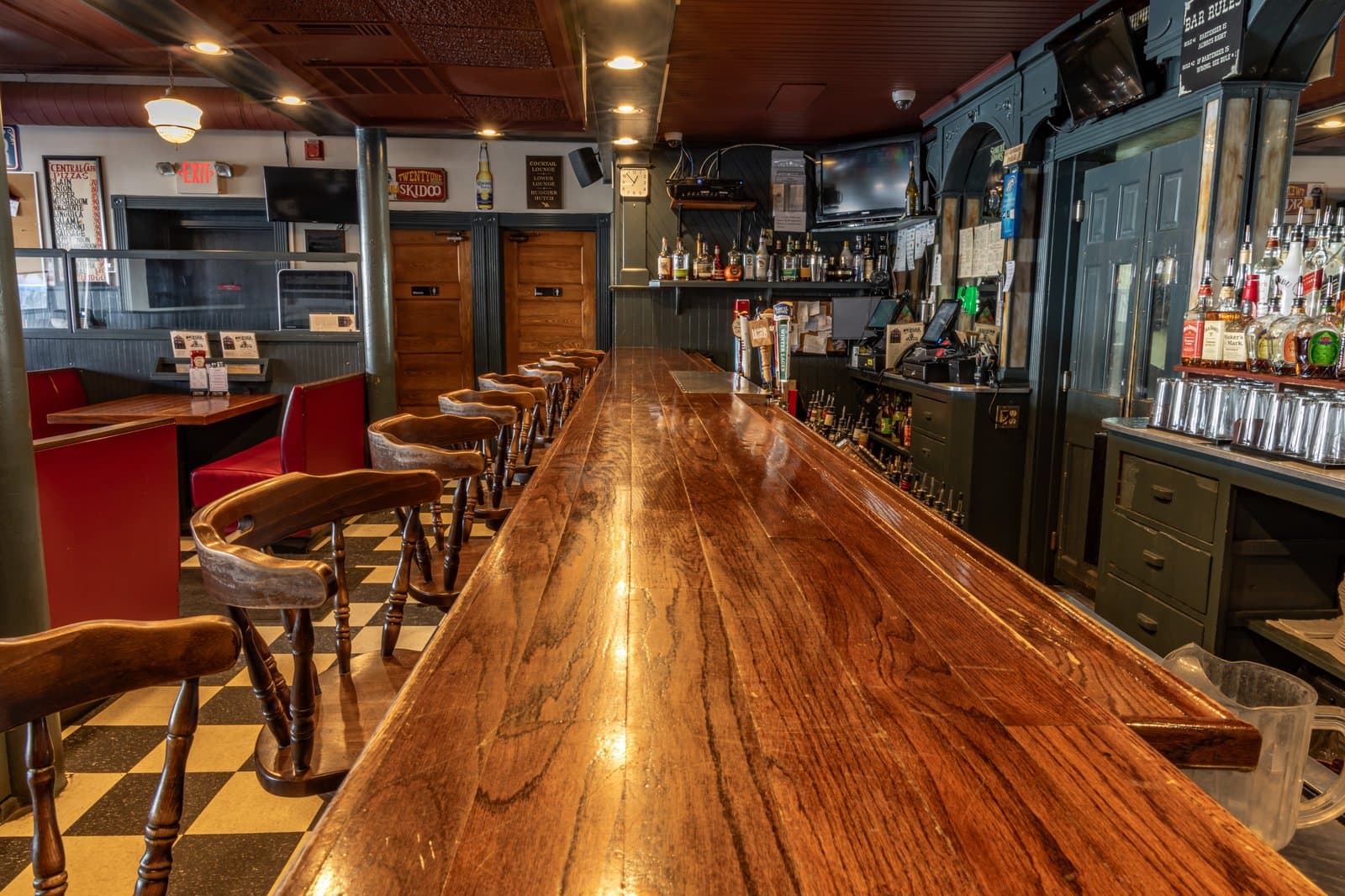 The hundred-year-old mahogany bar lined with wooden stools on a checkered floor