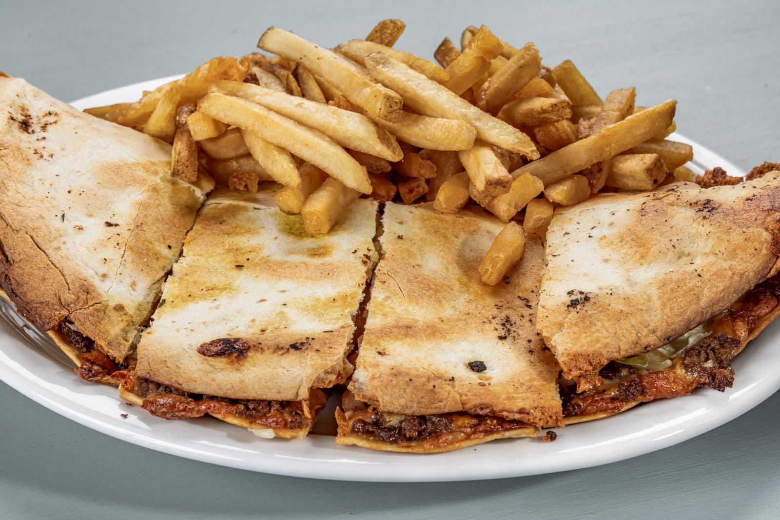 Grilled quesadilla quarters with a pile of french fries